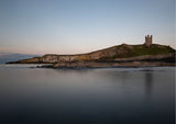 Lilburn Tower at Dunstanburgh Castle, perched on the dolerite rocks of the Great Whin Sill reflecting in the calm North Sea. - North East Captures
