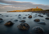 Boulder Beach, Death Rocks looking towards The Lilburn Tower at Dunstanburgh Castle perched on the dolerite rocks of the Great Whin Sill. - North East Captures